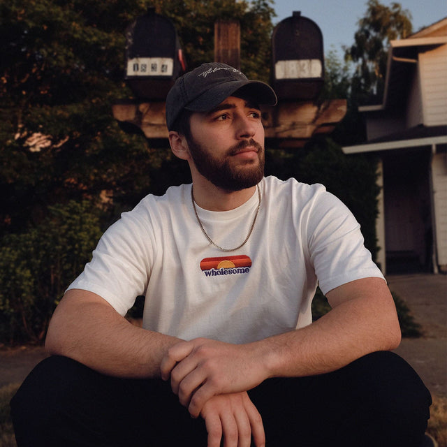 Wholesome Boy's white 'Sunrise Tee' with embroidered sunrise design and 'Wholesome' text, exuding a fresh and positive vibe.